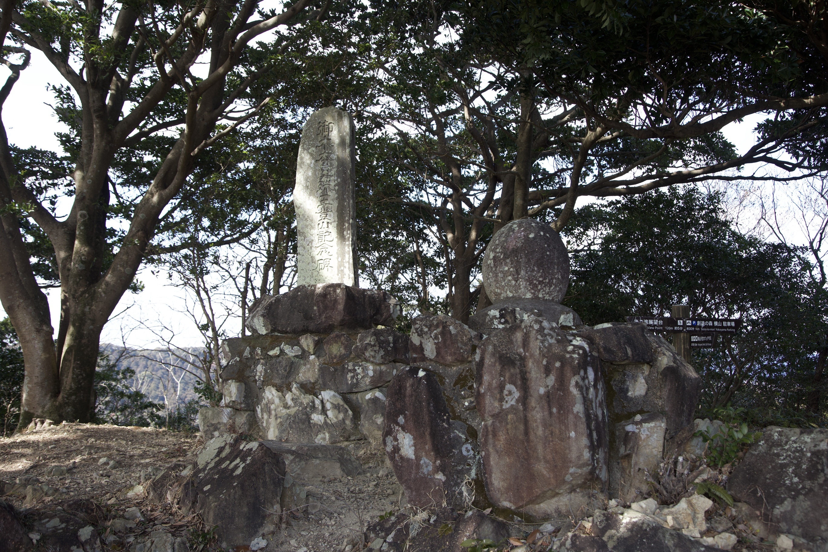 ミキモト真珠の記念碑の写真です。真珠のように丸い石の乗った記念碑の左に、御木本氏の登頂の記念碑が残っています。